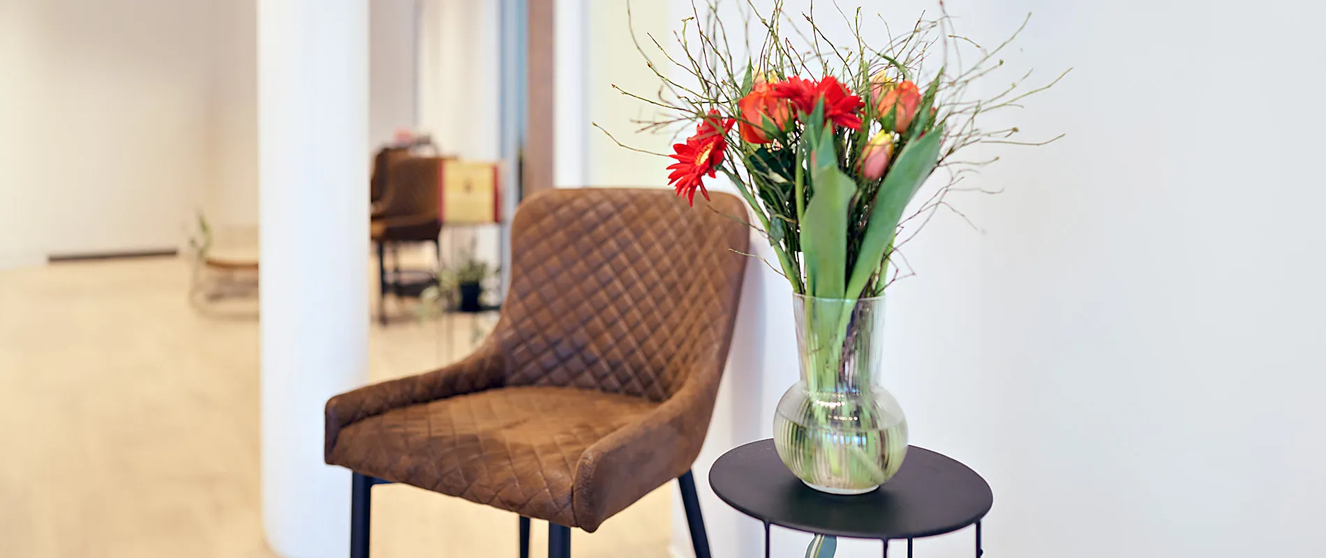 Wartebereich mit Ledersessel und Blumen